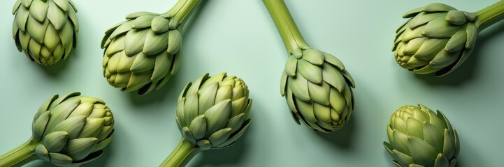 Fototapeta premium Fresh artichokes arranged on a pastel background, perfect for culinary, health, or organic food marketing.
