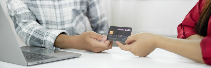 E-commerce Concept. Happy couple holding credit card enjoying doing online shopping and using laptop to enter their card number in-app to purchase and payment in the internet store