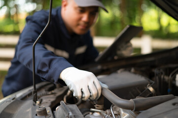 Asian male professional auto mechanic doing onsite service Open the bonnet to check for a broken...