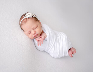 Sleeping Newborn Baby Wrapped In Swaddle Is A Studio Photo Of A Little Girl