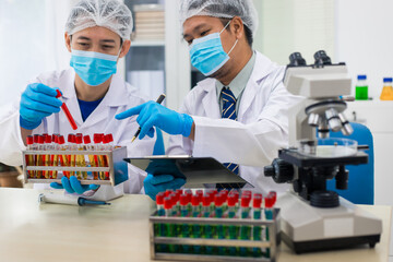 A modern laboratory scene showcasing scientists, both male , in lab coats, analyzing samples using microscopes and computers.