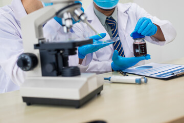 A modern laboratory scene showcasing scientists, both male , in lab coats, analyzing samples using...