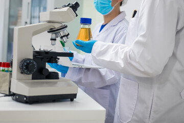 A modern laboratory scene showcasing scientists, both male , in lab coats, analyzing samples using...