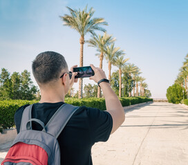 young man with a gray-red backpack behind his shoulders takes pi