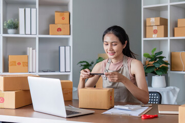 Female entrepreneur photographing packages for shipment at home