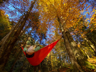 Relaxing in an Orange Hammock in Autumn Forest