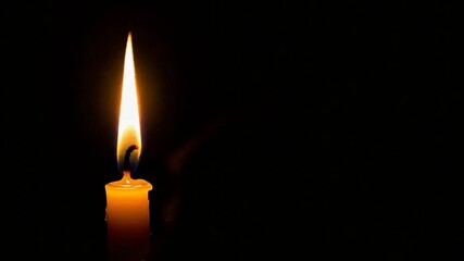 Single candle flame in dark background
