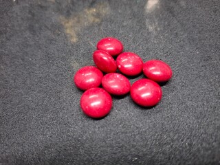 Bright red, round tablets often feature a smooth, glossy finish. Typically used for medications or supplements, they may vary in size and imprint, designed for easy identification and swallowing.
