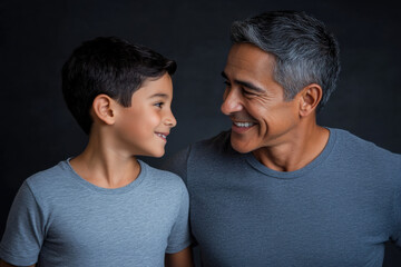 Fototapeta premium A studio portrait of an latin father and son looking at each other and smiling