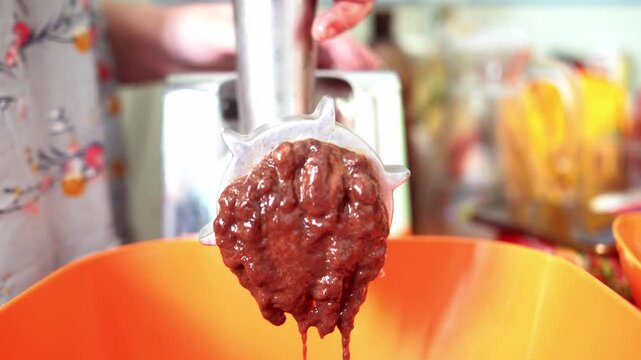 close-up of twisted beef liver being extruded through a meat grinder, showcasing its texture and the transformation from solid to a processed form