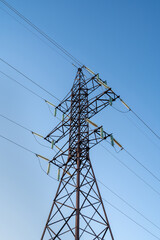 Electricity power pole with transmission lines against blue sky and clouds. Electrical power supply industry.