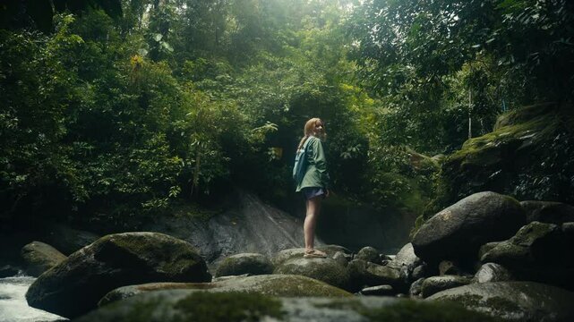 Young woman enjoying a tropical rainforest waterfall in the jungle 