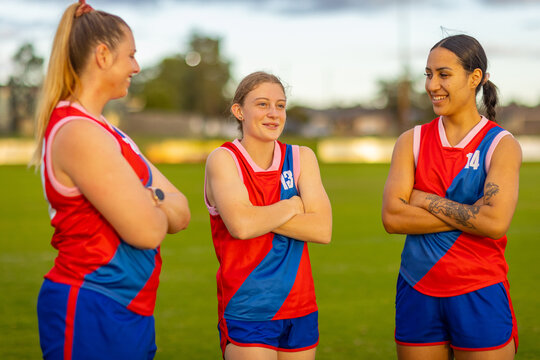 three young women on football field with their arms crossed