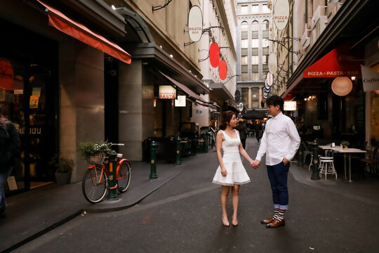 Man and woman holding hands in Melbourne laneway lined with restaurants