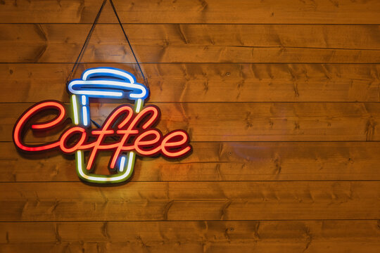 Neon coffee sign on wooden background in warm lighting