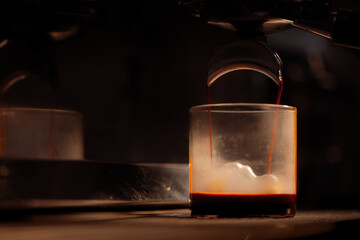 Espresso machine brewing coffee into a glass.