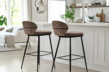 Fototapeta premium Pair of swivel bar stools with cream leatherette and dark wood frame, placed on an area rug in a modern kitchen with white cabinets and marble countertop.