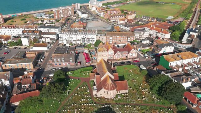 Saint Leonard's Church, located in Seaford, is captured from an aerial perspective. A cemetery adjoins the church. The town is situated along the coastline, surrounded by densely built houses.