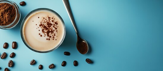 Obraz premium A glass of milky coffee rests on a white surface alongside a metal spoon and coffee beans A beaker holds black coffee fresh milk and coffee powder The background is blue for advertising purposes
