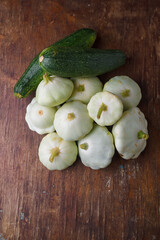 Heap of Patissons, some green pattypan or scallop squashes and zucchini on old brown wooden rustic...