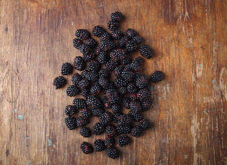 some fresh blackberries on brown wooden old rustic table background, closeup shot, copy space.