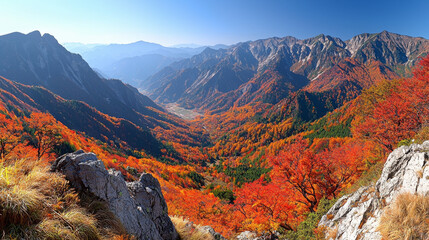 A stunning panorama of vibrant autumn foliage in a mountainous landscape under a clear blue sky.
