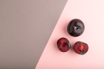 Purple Plum Cut in half pink and gray pastel paper, Top view, copy space