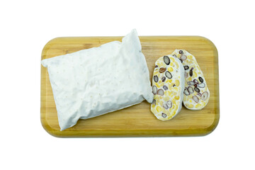 Fresh tempe or tempeh whole and sliced on wooden tray isolated on white background with clipping path top view flat lay, 5 mixed beans tempeh, white knitted mat of mycelium of Rhizopus oligosporus 