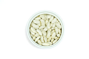 White beans or navy beans or pearl haricot beans or pea beans in white ceramic cup isolated on white background top view flat lay.