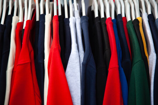 Close-up of assorted colourful jumpers and tops hanging side by side on a clothes rack in a shop