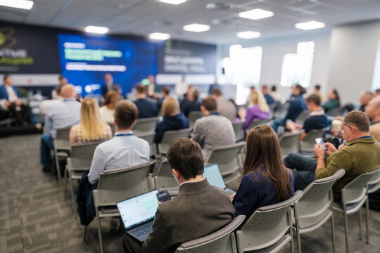 Conference attendees listening to panel discussion in modern hall. Business professionals engage in corporate event about UAV development. - Powered by Adobe