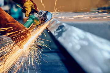 Industrial worker grinding metal with flying sparks