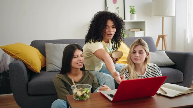 Student girl friends working together using laptop to study at home, while having healthy lunch
