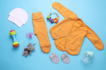 Set of newborn clothes, accessories and toys on a blue background. Flat lay. Top view