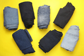 Rolled up jeans pants on yellow background. Top view