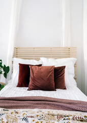 Elegant bedroom with wooden headboard, decorative pillows, and artistic wall decor in a bright, airy space
