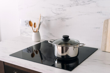 Stainless steel pan with lid at glass ceramic hob on kitchen