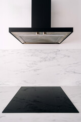 Modern induction stove with black cooker hood in kitchen room