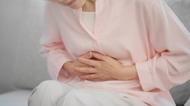 お腹を抱えるシニア女性	

