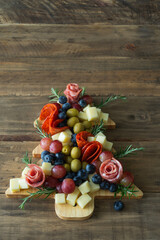 A wooden tray with a tree shape is filled with various types of food. Vertical photo.