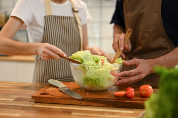 Cropped shot of young couple enjoys preparing a delicious and healthy salad together in a kitchen
