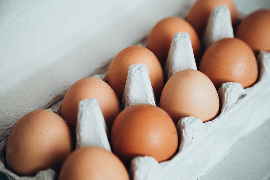 Fresh brown eggs in a cardboard carton on white background