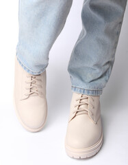 Female legs in jeans and white leather boots on white background. Fashion concept
