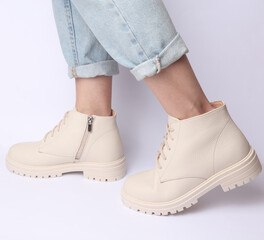 Female legs in jeans and white leather boots on white background. Fashion concept