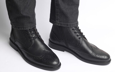 Male legs in black leather brogue boots on a white background