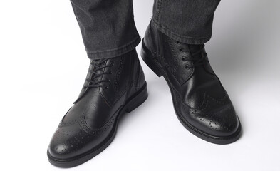 Male legs in black leather brogue boots on a white background