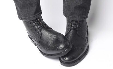 Male legs in black leather brogue boots on a white background