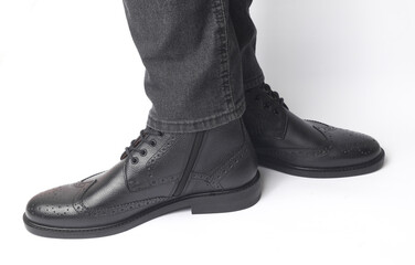 Male legs in black leather brogue boots on a white background