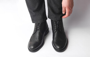 Male legs in black leather brogue boots on a white background