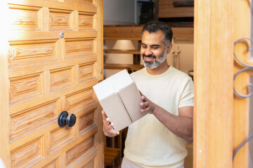 Middle-aged indian man receiving a package at home